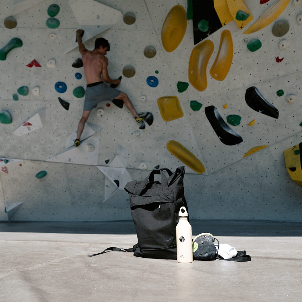 Mann klettert an Boulderwand, eoto Rucksack im Vordergrund