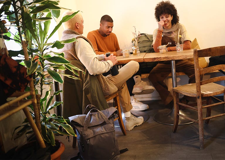 Eine Freundesgruppe von drei Jungen Leuten sitzen zusammen im Cafe Eine Freundesgruppe von drei Jungen Leuten sitzen zusammen im Cafe