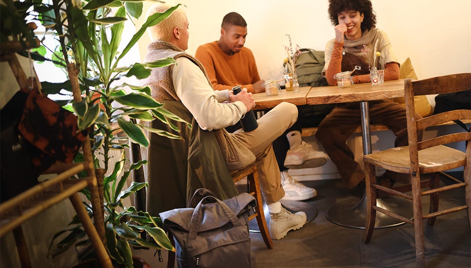 Eine Freundesgruppe von drei Jungen Leuten sitzen zusammen im Cafe Eine Freundesgruppe von drei Jungen Leuten sitzen zusammen im Cafe