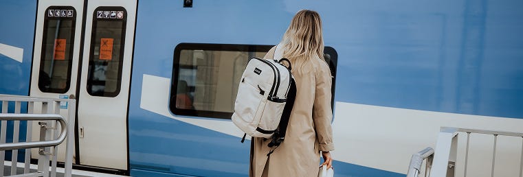 Person mit eoto Daypack steht am Bahnhof, Zug fährt gerade ein