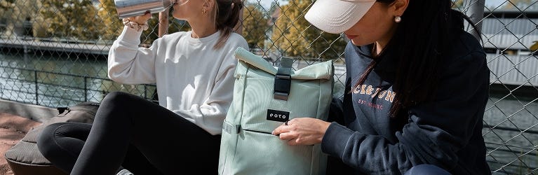 eoto Rolltops 2 Personen mit eoto Rucksäcken sitzen am Sportplatz