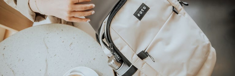 eoto Rucksäcke für Uni & Arbeit Person packt Laptop in Rucksack, Nahaufnahme