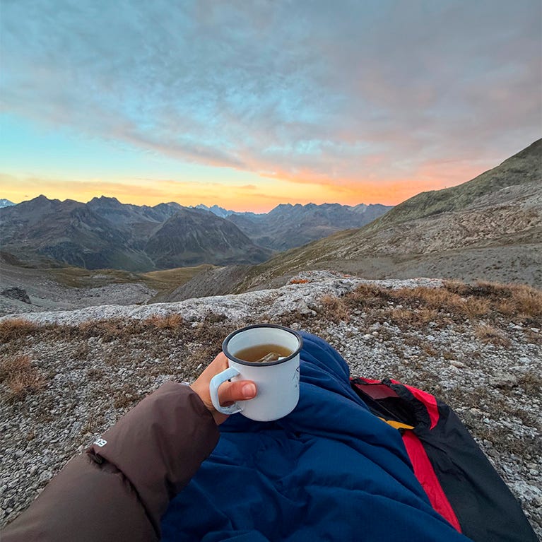 Person mit Kaffee bei Sonnenaufgang beim Nowhere Hike Person mit Kaffee bei Sonnenaufgang beim Nowhere Hike