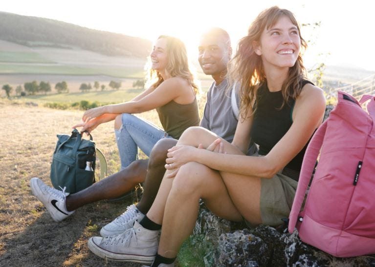 Über eoto Freunde sitzen auf Wiese mit eoto Rucksäcken