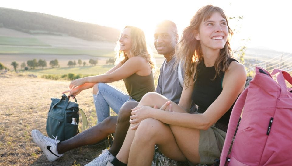 Über eoto Freunde sitzen auf Wiese mit eoto Rucksäcken