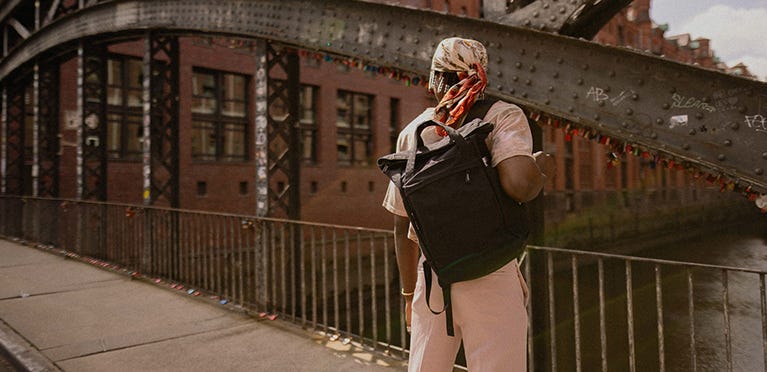 Person mit eoto-Rucksack steht auf einer Brücke in der Stadt
